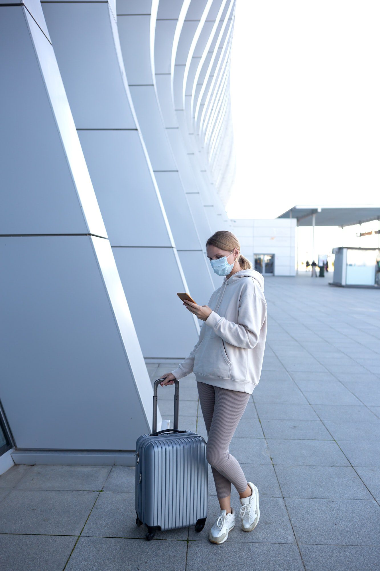 young woman with suitcase waiting for check-in at the entrance to the airport