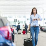 Smiling woman walking with luggage on Buffalo Airport parking lot